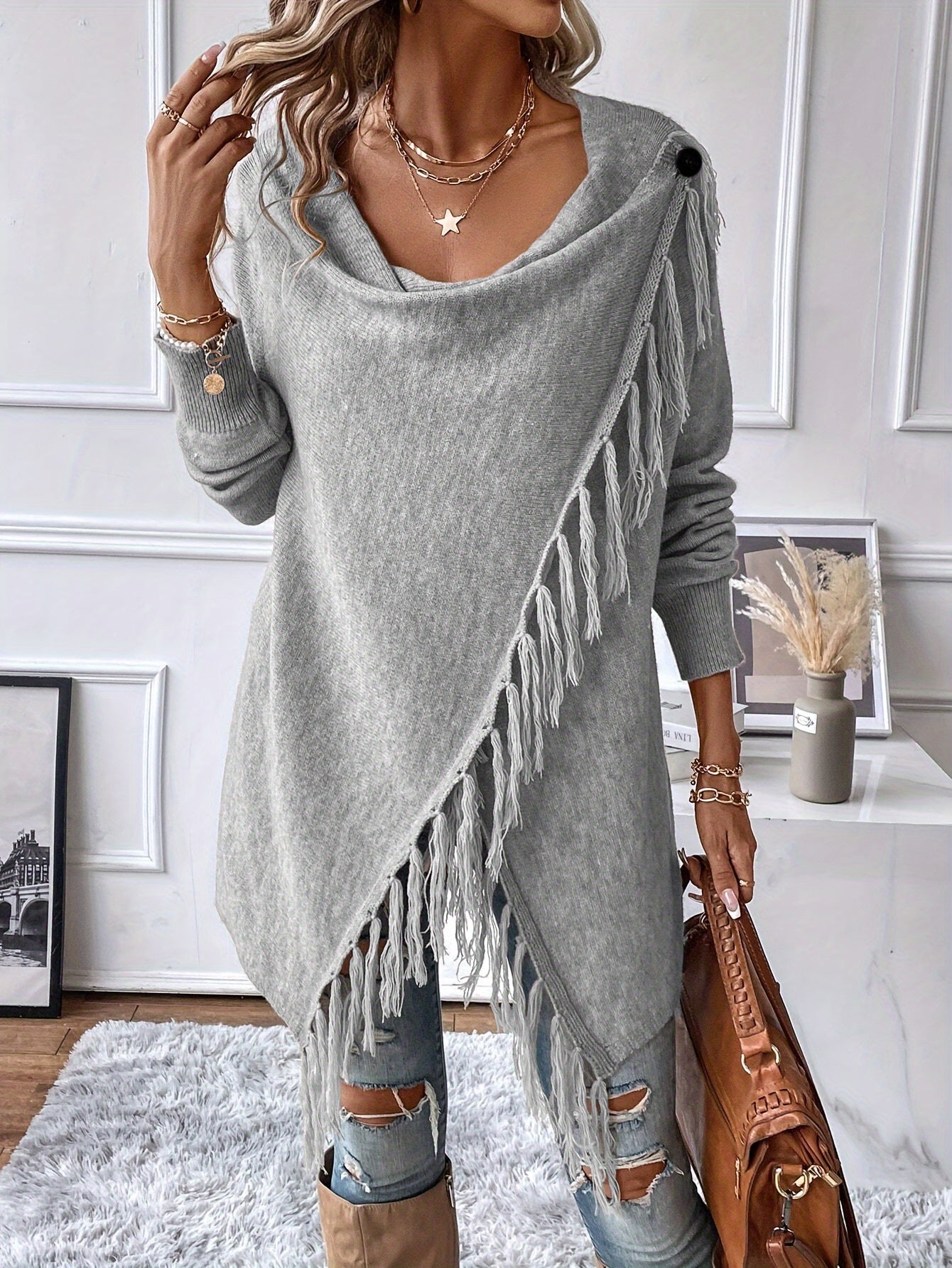 Woman wearing a gray fringe sweater in a room with decor elements.