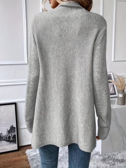 Person wearing a gray sweater in a room with white walls and decor.