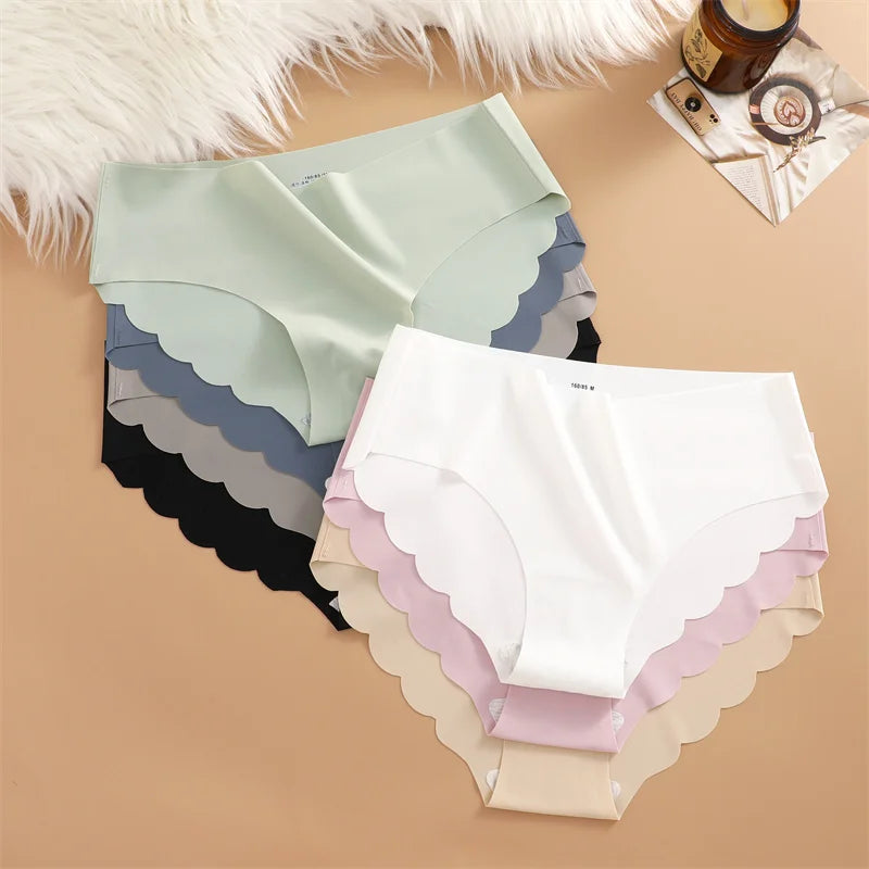 Set of women's underwear with scalloped edges in various colors on a beige surface.
