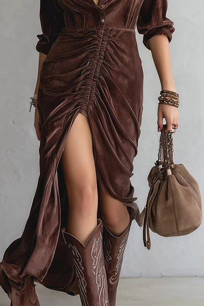 Person wearing a brown dress with a slit and cowboy boots, holding a matching brown handbag against a plain background.