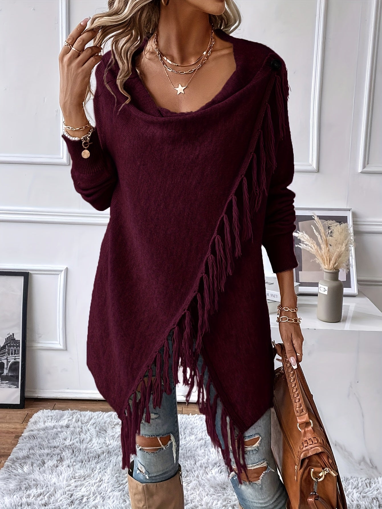 Person wearing a burgundy fringe sweater in a room with decor elements.
