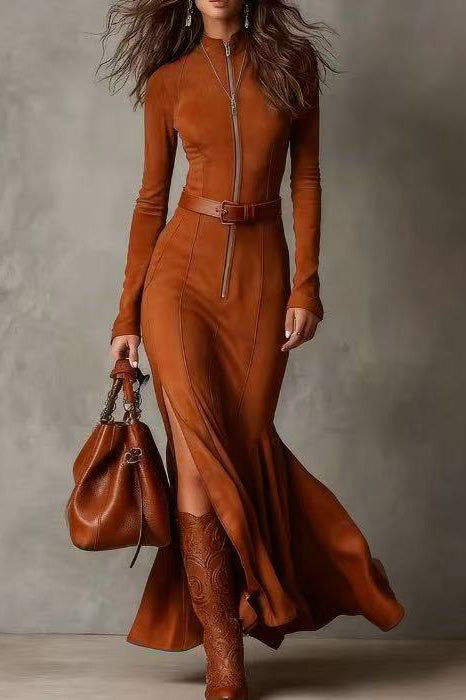 Woman wearing a brown dress with a belt and holding a matching handbag against a gray background