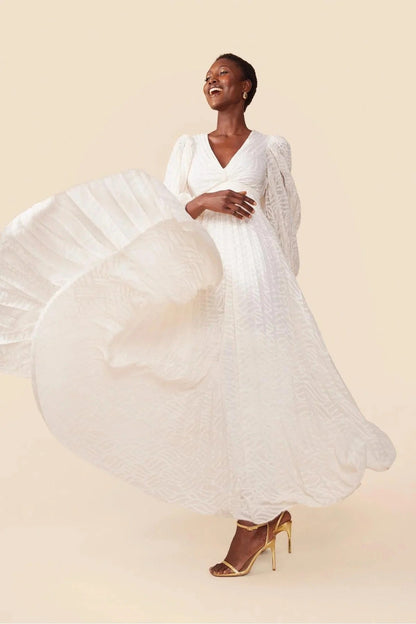 Woman in a flowing white dress on a beige background